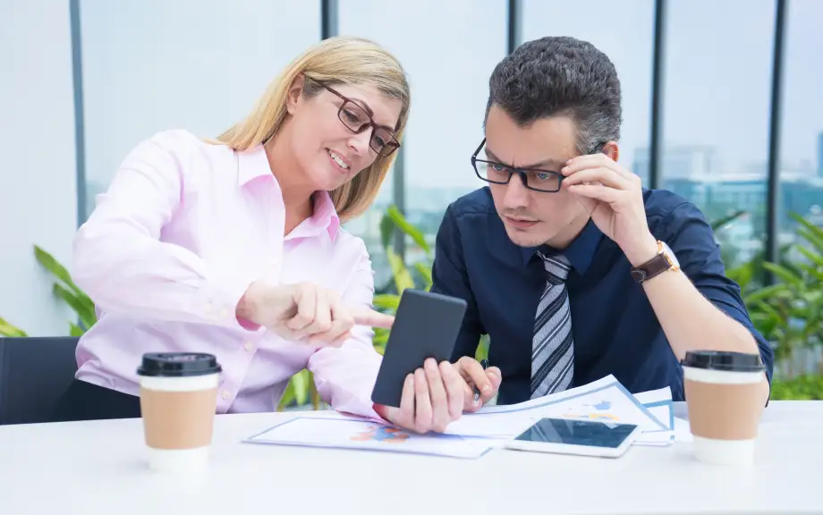Dos colegas de oficina revisando información en un teléfono móvil